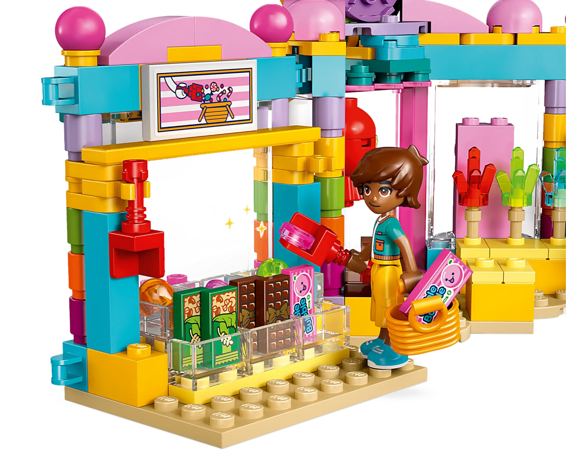 A LEGO figure with a basket stands before the LEGO® Friends Heartlake City Candy Store by Legos - Toyhouse, complete with candy pieces and a checkout counter—ideal for imaginative pretend play.