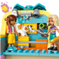 Two toy figures play in the LEGO® Friends Pet Accessories Shop by Legos - Toyhouse, featuring a white and orange cat, scissors, a brush, and wall decorations—ideal for animal-care pretend play.