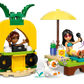 Two LEGO Friends minifigures enjoy the Unicorn & Flamingo Pool Party from Legos - Toyhouse: one DJs in a pineapple booth, the other relaxes under an umbrella with drinks while a white cat lounges nearby—perfect for expanding your set.
