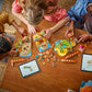 Three children build the LEGO® Friends Family Vacation Beach Resort set by Legos - Toyhouse on a wooden table, using instructions displayed on two tablets amid scattered pieces.