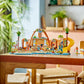 The LEGO® Friends Family Vacation Beach Resort by Legos - Toyhouse is built on a wooden dining table in a modern, bright room with wooden chairs and indoor plants.
