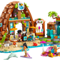 The LEGO® Friends Family Vacation Beach Resort by Legos - Toyhouse features minifigures, a resort building, palm trees, a yellow slide, surfboards, a dolphin, and fun beach accessories for kids.