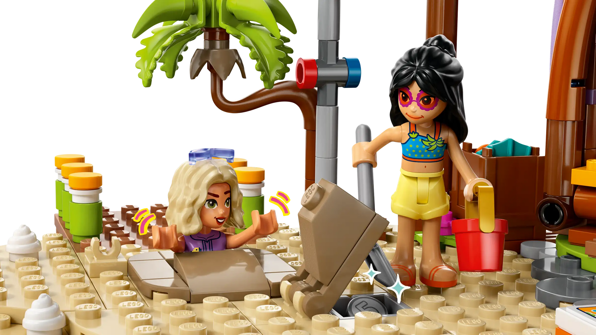 At the LEGO® Friends Family Vacation Beach Resort by Legos - Toyhouse, two figures have fun: one with a red bucket and shovel, and another buried in sand with just their head and arms showing—perfect for kids’ creative play!.