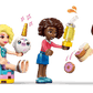 At the Legos - Toyhouse LEGO® Friends Unicorn Dream Café, one mini-figure sits with a unicorn, another stands holding a trophy, and a third raises an arm while holding a plate of donuts.
