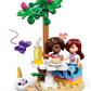 Two mini-dolls sit at a round outdoor table with food and drinks under a tree at the LEGO® Friends Unicorn Dream Café by Legos - Toyhouse, with a purple butterfly and unicorn café figure nearby.