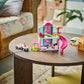 A LEGO® Disney™ Minnie's Pet Hotel set by Legos - Toyhouse, featuring a pink slide and mini figures, is displayed on a round wooden coffee table in a cozy living room.