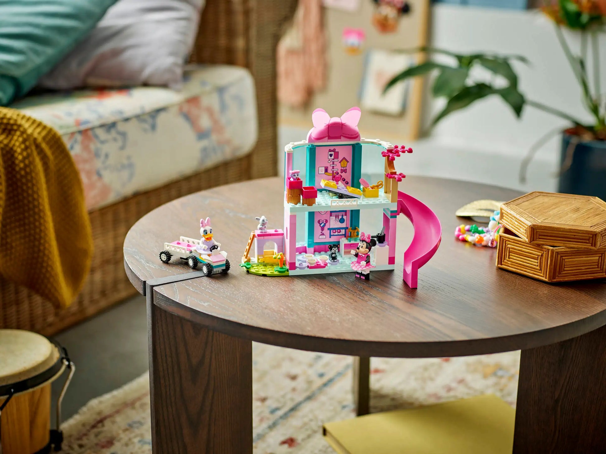 A LEGO® Disney™ Minnie's Pet Hotel set by Legos - Toyhouse, featuring a pink slide and mini figures, is displayed on a round wooden coffee table in a cozy living room.