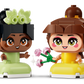 Two LEGO® Disney™ Mini Belle & Tiana with Castle figures from Legos - Toyhouse stand together, smiling in colorful dresses as one holds pink flowers—perfect for imaginative adventures.