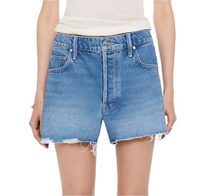 A person wears Mother’s The Main Course Short Fray—high-waisted, loose-fit denim shorts with frayed hems made from recycled cotton—paired with a white sleeveless top.