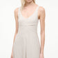 A woman models the Madison Linen Dress by Staud—a sleeveless, light beige stretch linen dress with a V-neckline—standing against a plain white background.