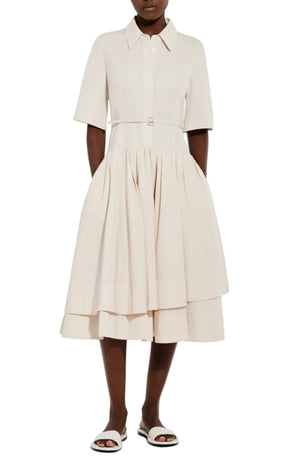 A person wearing the CO Short Sleeve Belted Cotton Poplin Dress—a light beige shirt dress with a collared neckline, full skirt, and short sleeves—pairs it with white sandals for perfect summer style.