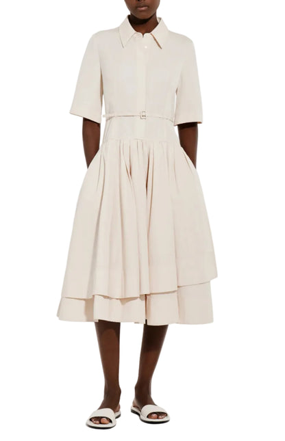A person wearing the CO Short Sleeve Belted Cotton Poplin Dress—a light beige shirt dress with a collared neckline, full skirt, and short sleeves—pairs it with white sandals for perfect summer style.