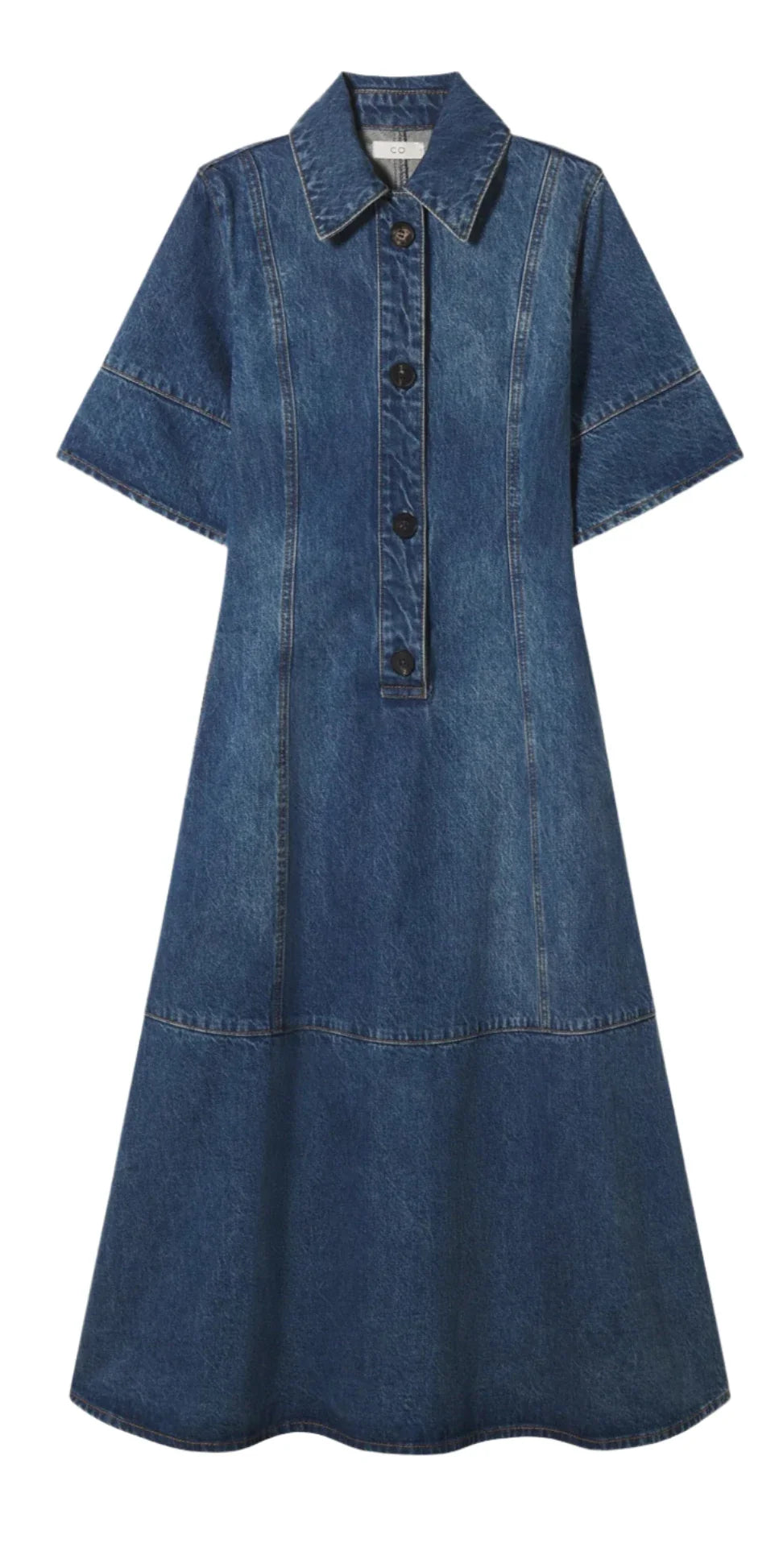 The CO Denim Midi Dress by CO is a knee-length, short-sleeve denim dress crafted from 100% cotton, and it features a collar, front button placket, and intricate seam detailing.