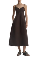 A person wearing the CO Bustier Cut Dress in dark brown cotton poplin with thin straps and black sneakers, standing against a white background.