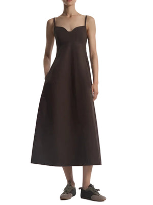A person wearing the CO Bustier Cut Dress in dark brown cotton poplin with thin straps and black sneakers, standing against a white background.