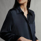 A woman is seen in a partial, close-up view against a plain background, showcasing the TWP Jenny's Silk Gown from TWP.