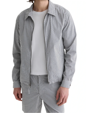 A person wearing a white t-shirt, the AG Jeans Philip Zip Jacket, and matching striped pants stands against a white background.