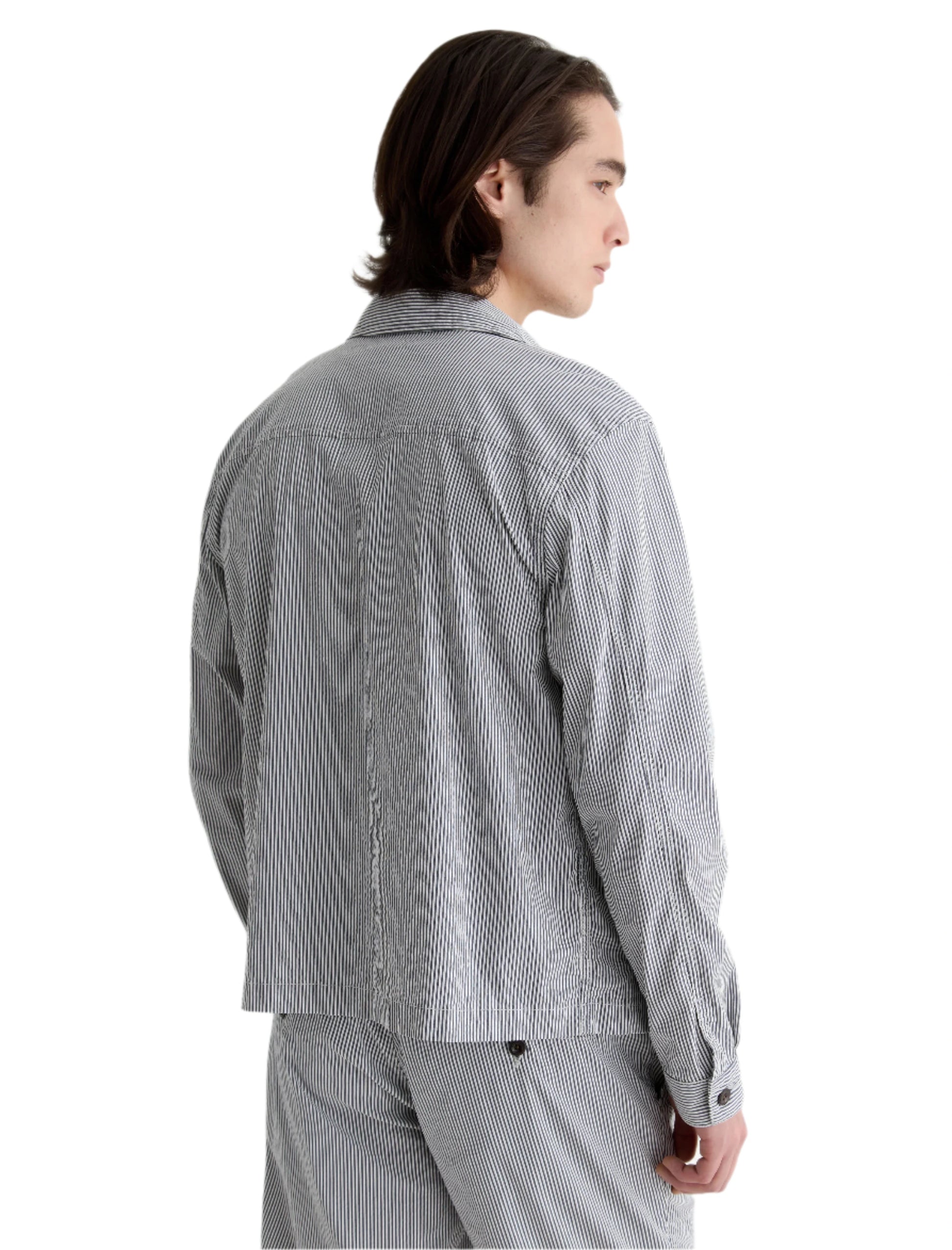A person with medium-length dark hair is wearing an AG Jeans Philip Zip Jacket, standing and facing away at an angle against a white background.