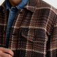 A person wearing a brown and tan houndstooth Grant Overshirt layered over a denim jacket.