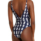 The individual is sporting the Lenny Niemeyer Rec Cachecoeur One Piece, a stylish cross-body swimsuit in navy and white, featuring a deep V-back and crafted from BIO Lycra for enhanced comfort and UV protection.