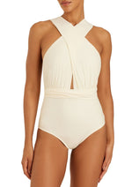 A person is wearing the Lenny Niemeyer Chic One Piece, a cream-colored swimsuit featuring a crisscross halter-neck design that provides biodegradable UPF 50+ UV protection.