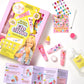 The Super Smalls Create Your Own Lip Gloss kit features kid-safe ingredients and includes tubes, glitter, stickers, flavor oil, a syringe, a mixing cup, and step-by-step instructions—all artfully arranged on a white surface for an exciting DIY lip gloss activity.