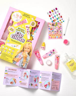 The Super Smalls Create Your Own Lip Gloss kit features kid-safe ingredients and includes tubes, glitter, stickers, flavor oil, a syringe, a mixing cup, and step-by-step instructions—all artfully arranged on a white surface for an exciting DIY lip gloss activity.