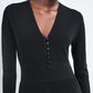 A person wearing the Maria McManus Button Front Dress, featuring long sleeves, a deep V-neck, and elegant corozo nut buttons down the front.