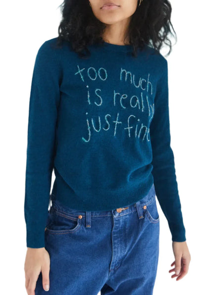 A person wearing the Lingua Franca "Too Much Is Really Just Fine" Crewneck Sweater, made of responsibly sourced cashmere, paired with blue jeans.