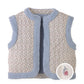 The Girls’ Eulalia Floral Reversible Vest from Gingersnaps features a sleeveless quilted design with blue sherpa trim and a ditsy floral print, highlighted by an inset showing a small embroidered flower detail on the fabric.