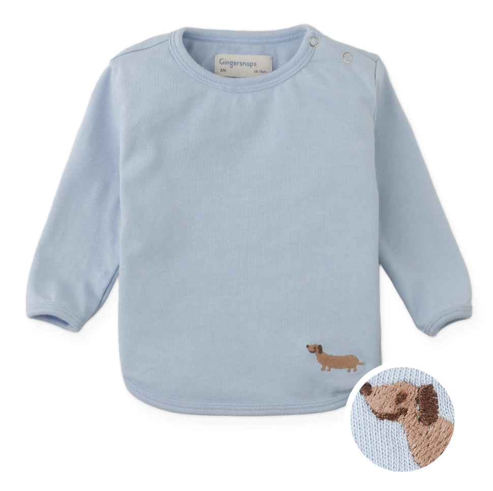 Dress your little one in the Baby Boys’ Teo Jersey Tee from Gingersnaps—a light blue, long-sleeved shirt featuring a small embroidered brown dachshund on the lower right front, styled for a playful yet polished modern city look.