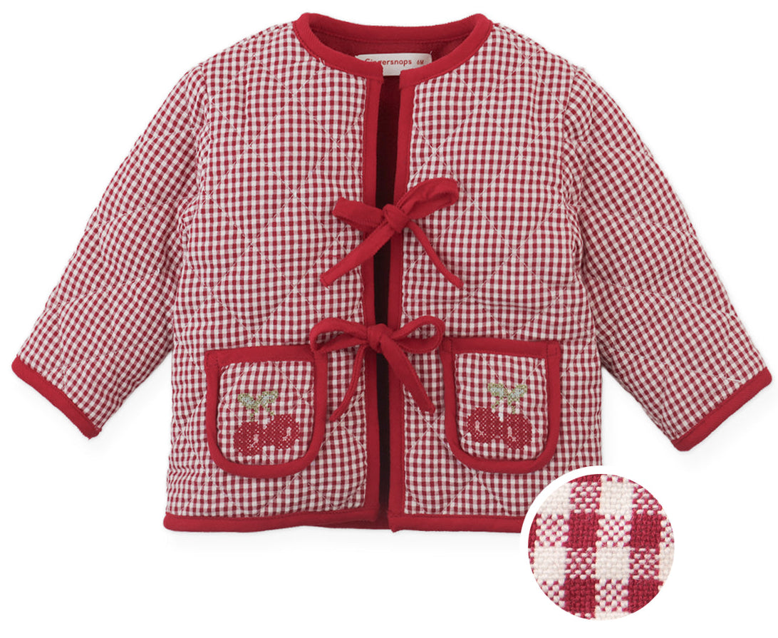 The Gingersnaps Baby Girls’ Lavinia Boxy Quilted Coat features a red and white gingham pattern with two front pockets adorned with cherry embroidery; a close-up inset highlights the textured fabric and playful bow-tie details that provide a charming finishing touch.