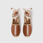 The Gaia Whipstitched Flat by Stella McCartney is a pair of brown leather espadrilles with woven soles and beige ribbon ankle ties, showcasing natural textures and a handcrafted finish, displayed side by side on a white background.