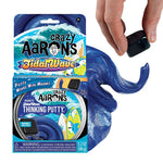 A hand hovers a magnet above Crazy Aarons Tidal Wave Magnetic Storm Thinking Putty, making the blue, magnetic putty swirl and shift. Both the product packaging and sensory toy are visible together.