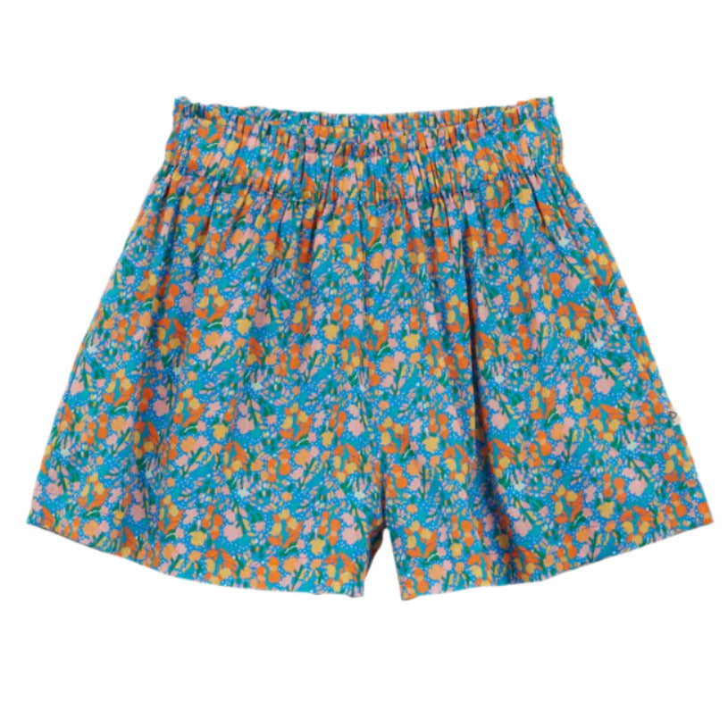 Girls' Fraise Short by Arsene & Les Pipelettes features an elasticized waist and an orange, green, and purple floral pattern on blue fabric, shown against a white background.
