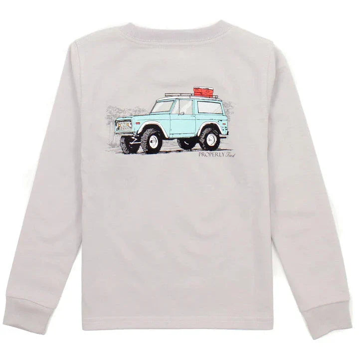 Introducing the Properly Tied Baby Signature LS Shirt, a classic design boasting a gray long-sleeve adorned with an illustration of a light blue SUV carrying luggage on the roof, all crafted from incredibly soft Pima Cotton for maximum comfort.