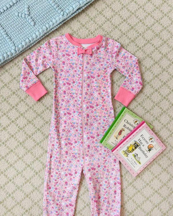 A pink Baby Girl's Noelle's Night Night sleeper by The Beaufort Bonnet Company is laid out on a carpet next to three children’s books, including some from the Winnie-the-Pooh series.