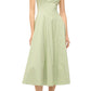A person in Staud's Wells Dress—light green, sleeveless, ankle-length cotton poplin with a corset-like fit—stands in sandals against a neutral background.