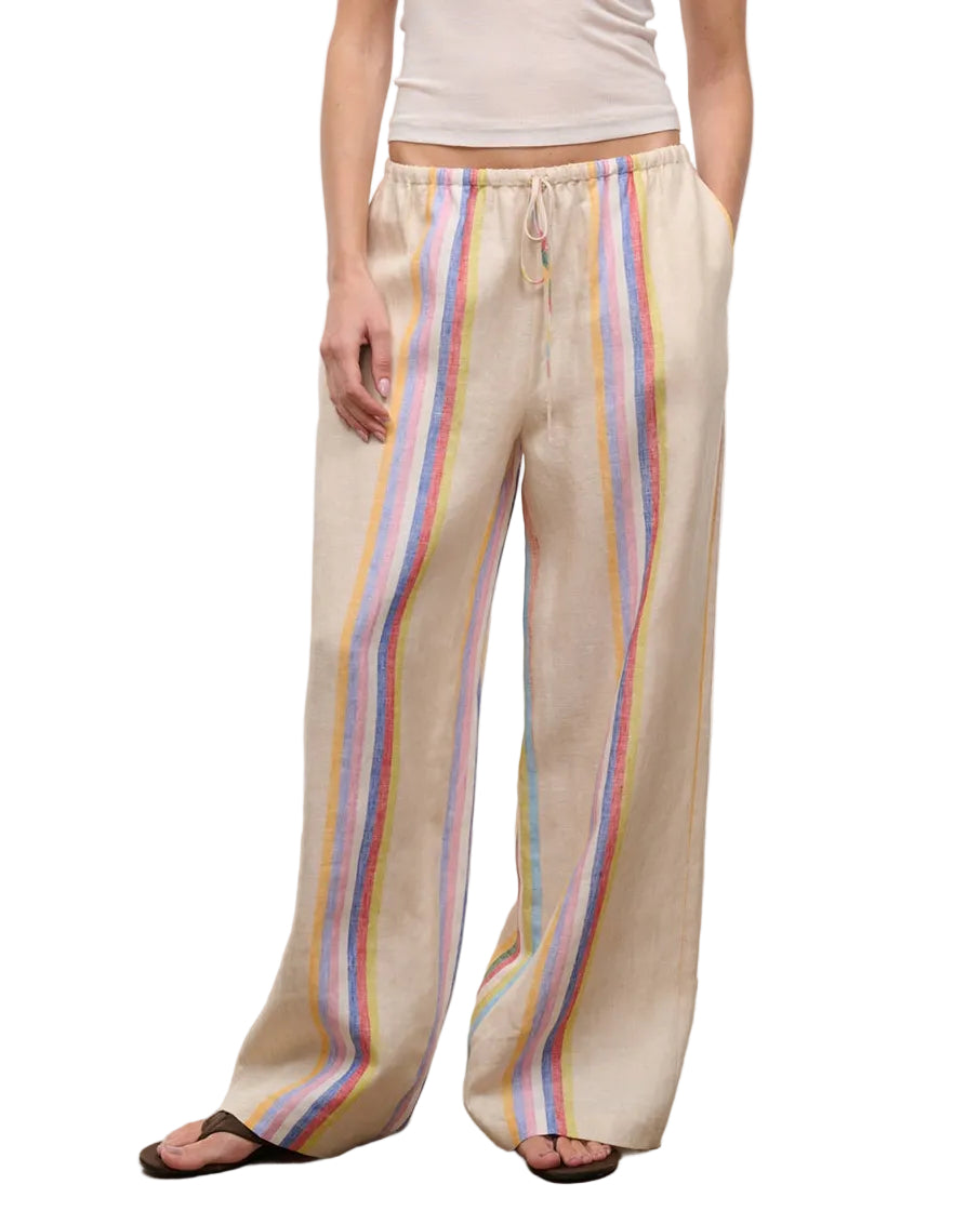 A person wears Staud's Mateo Linen Pant—relaxed fit, beige with vertical rainbow stripes—paired with a white sleeveless top and sandals, making it a perfect warm-weather look.