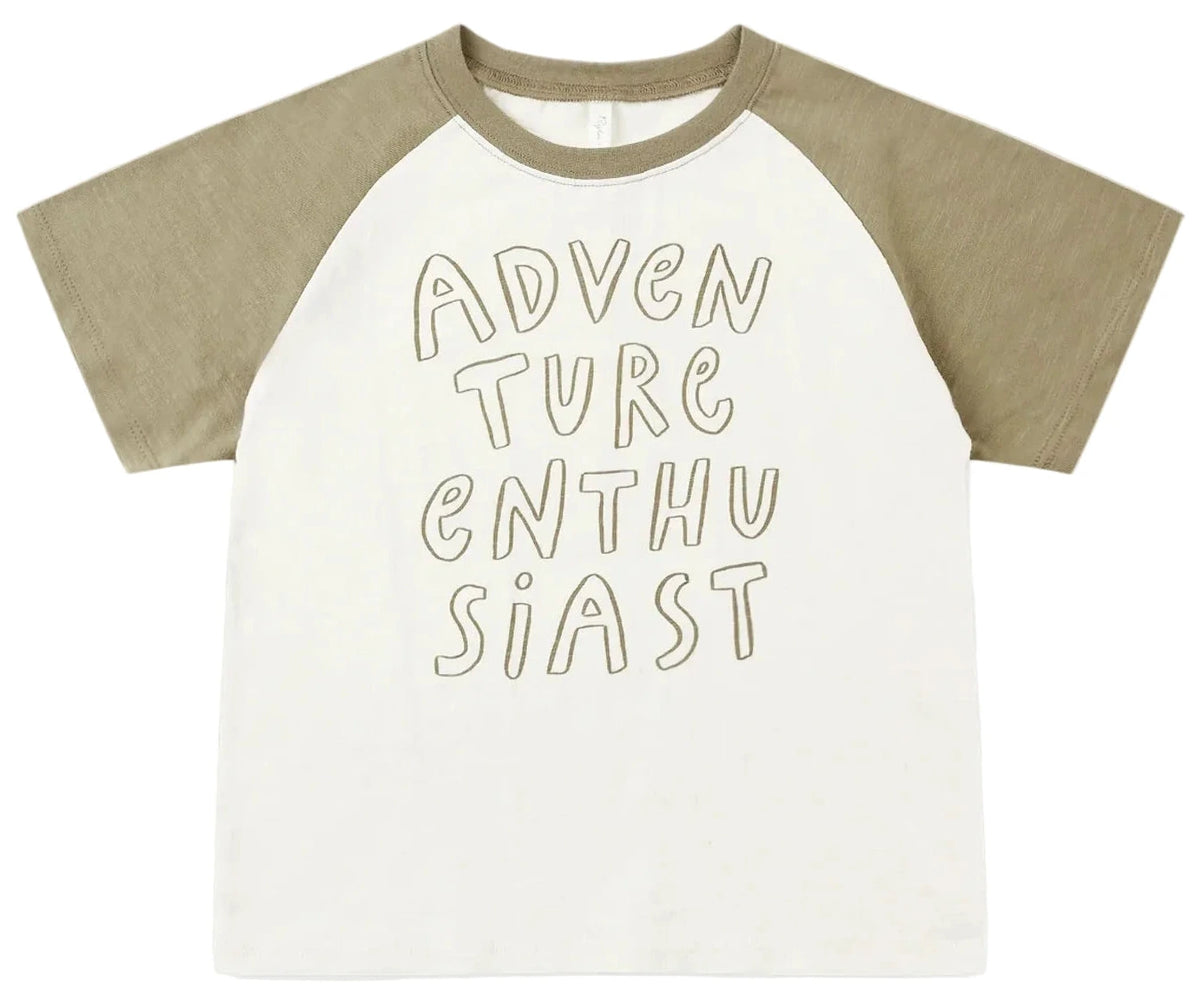 The Rylee & Cru Baby Boys’ and Boys’ Raglan Short Sleeve Tee features khaki raglan sleeves and a white cotton jersey body, with “ADVENTURE ENTHUSIAST” displayed in bold handwritten-style lettering on the front.