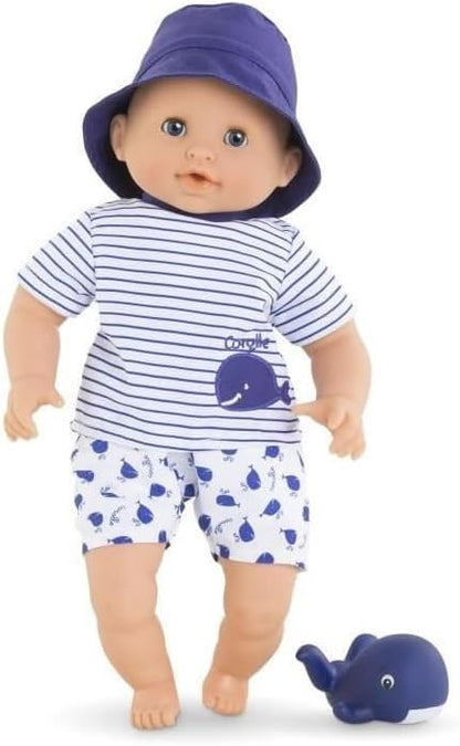 The Corolle Bebe Bath Doll wears a blue hat, whale-print striped shirt, and matching shorts, and comes with a small blue toy whale—an ideal water-play companion for bath time.