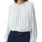 A person wearing the Simkhai Frida Top—a white silk georgette blouse with blouson sleeves—tucked into high-waisted blue denim jeans creates a fluid silhouette.