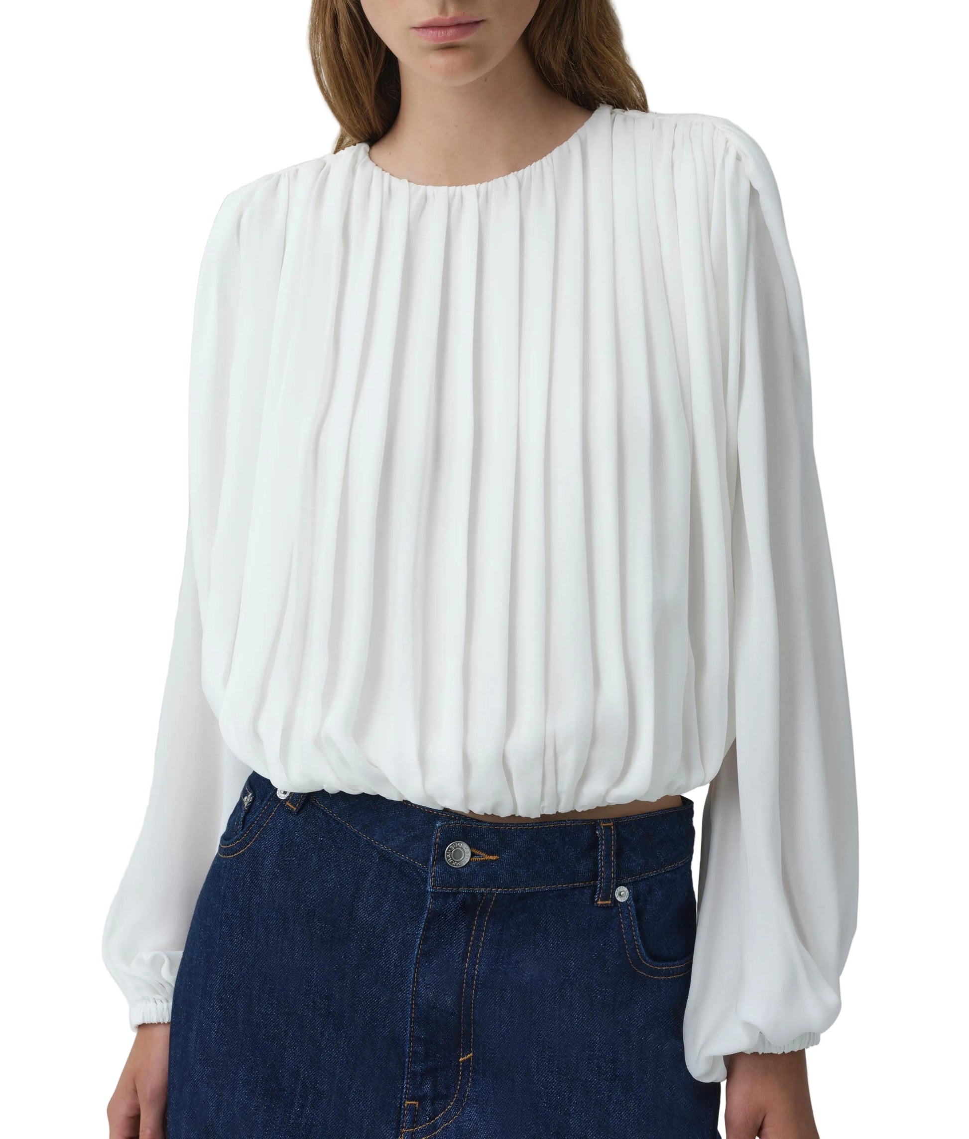 A person wearing the Simkhai Frida Top—a white silk georgette blouse with blouson sleeves—tucked into high-waisted blue denim jeans creates a fluid silhouette.