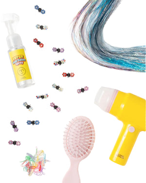 The Hairstyle Hero Salon Kit by Super Smalls includes striking hair extensions, colorful accessories, a spray bottle, yellow hair dryer, and pink detangling brush on a white background.