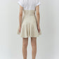 A woman faces away in the Simkhai Sundae Linen Mini Dress, featuring a structured bodice and beige flared skirt. Her long dark hair and light-colored heels complete an effortlessly elegant look.