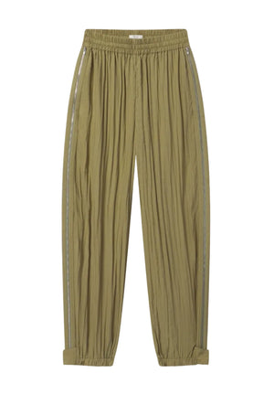 The Articulated Vented Pant by CO is crafted from lightweight technical fabric in light olive green, featuring crinkled texture, elasticated waist, zip pockets, side stripes, and adjustable cuffs.