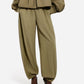A person wears the CO Articulated Vented Pant in olive green lightweight technical fabric with pleats, elasticated waist and cuffs, paired with black pointed-toe heels. Only the lower half of the outfit is visible.