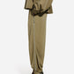 A person in side profile wears CO’s olive Articulated Vented Pant with an elastic waist, a matching top, and dark green pointed heels, set against a plain white background.
