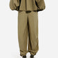 Model wears CO’s Articulated Vented Pant in olive with an elastic waist, styled with a matching oversized top and black pointed heels, shown from the back against a plain white background.