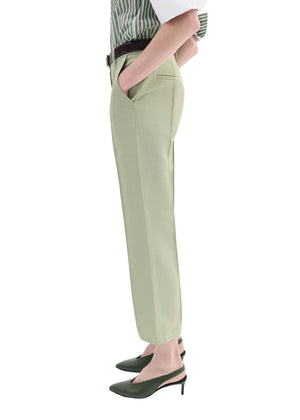 A person in side profile, hand in pocket, wears CO's Cropped Flared Pant in light green with a striped shirt, black belt, and dark green pointed-toe heels.